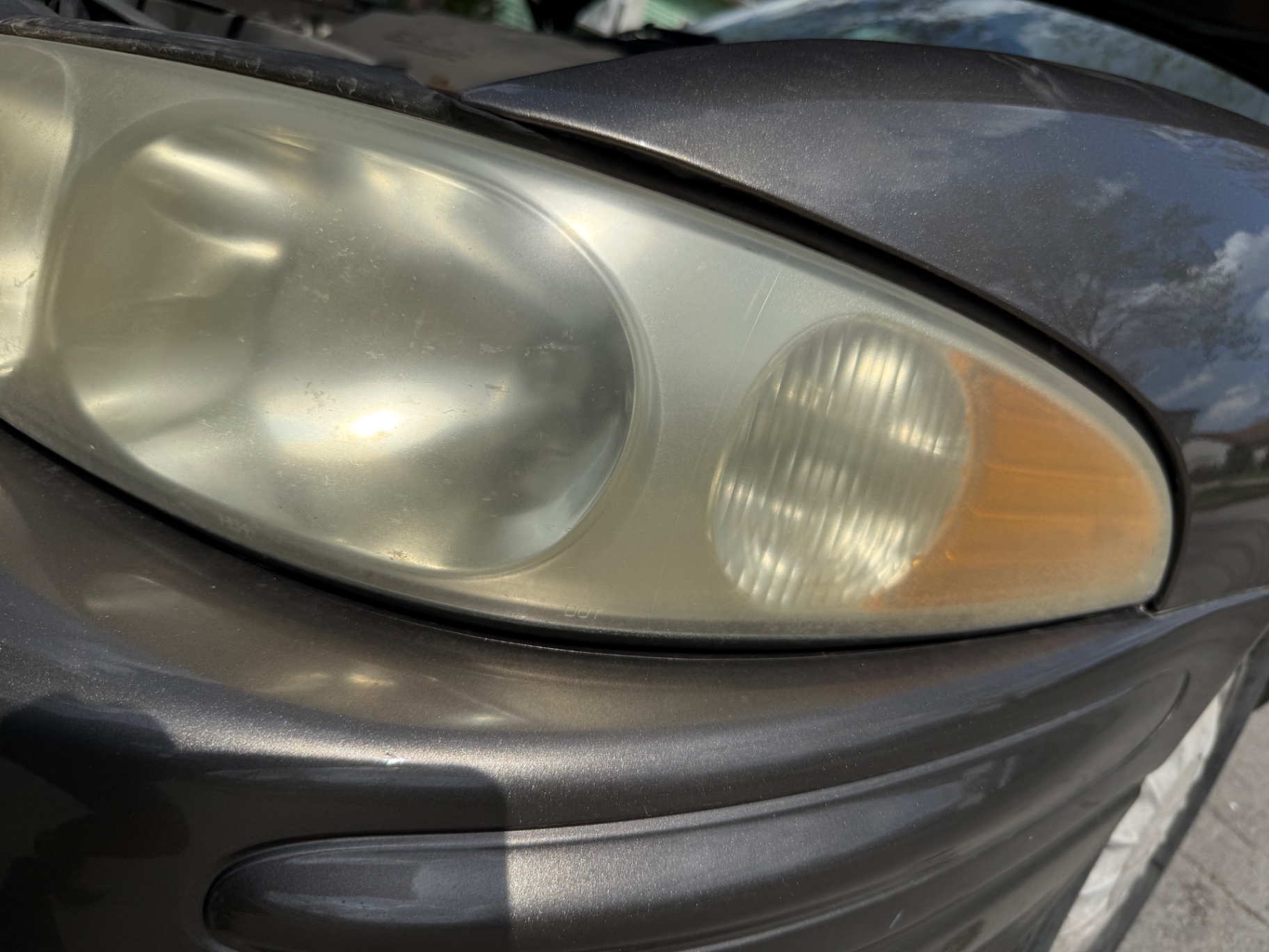 Yellowed passenger side headlight lens with heavy oxidation before restoration