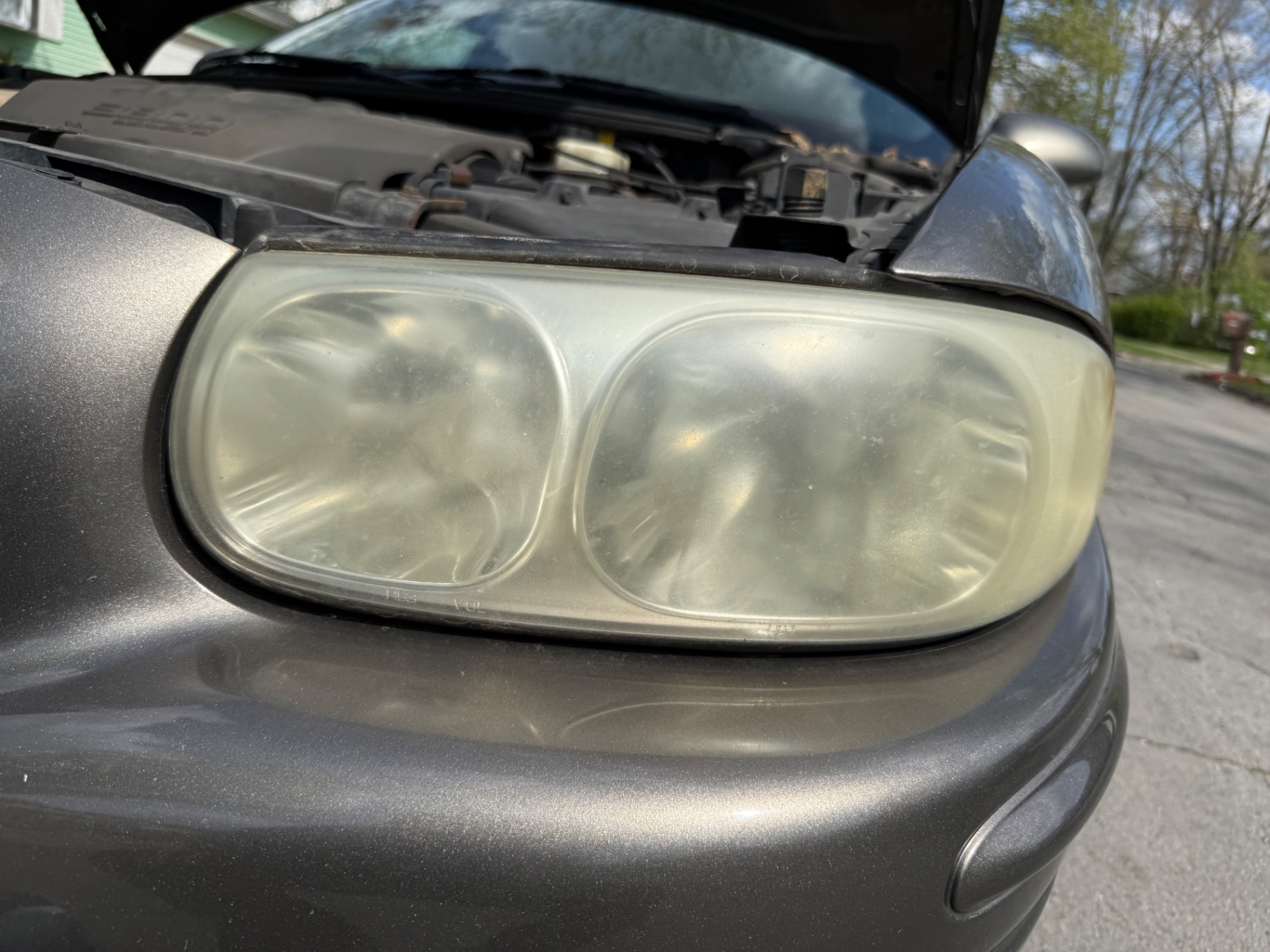 Cloudy, oxidized driver side headlight on a gray Buick before restoration in Columbus, Ohio